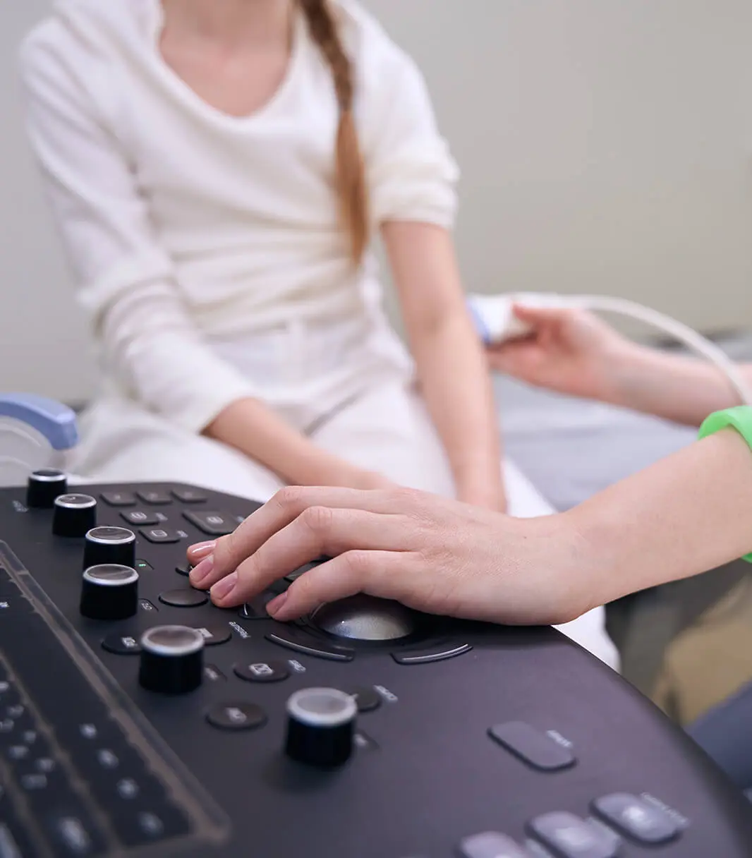 Hände einer Ärztin führen eine kinderurologische Ultraschalluntersuchung an einem Kind durch.